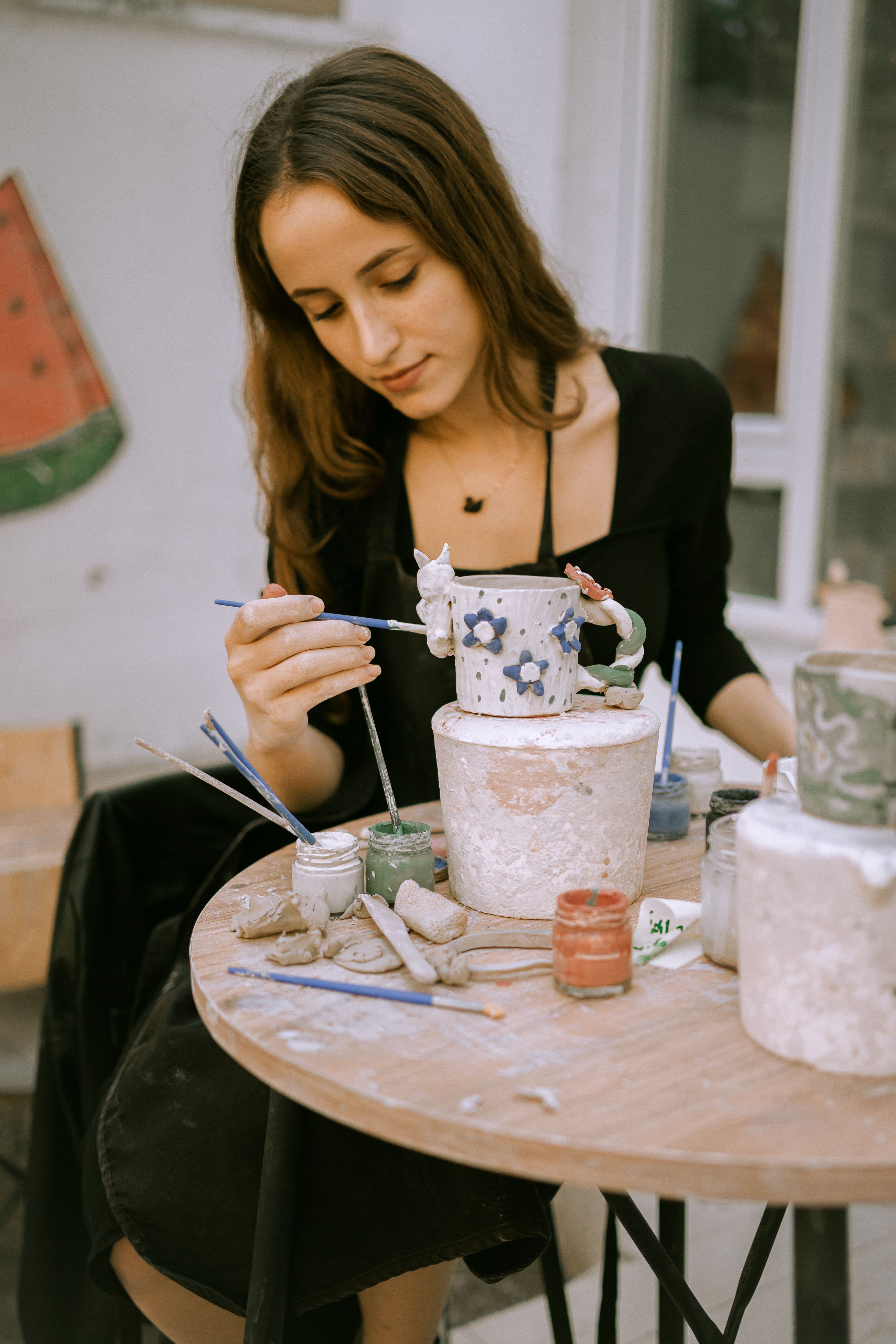 Artisan hand-painting ceramic pottery in her studio